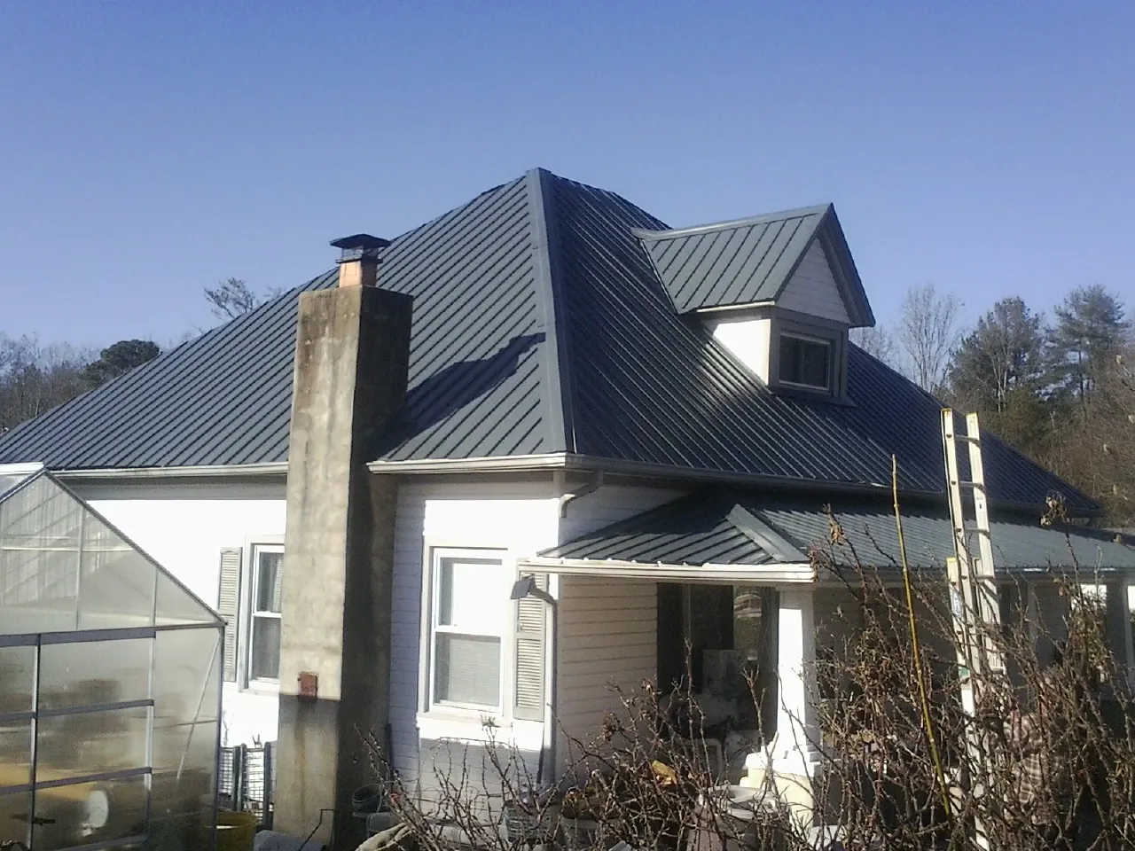 Dark blue standing seam metal roof on a white farmhouse with dormer — Slate & Tile Roof Repair by Roofing Brothers in Jackson Center