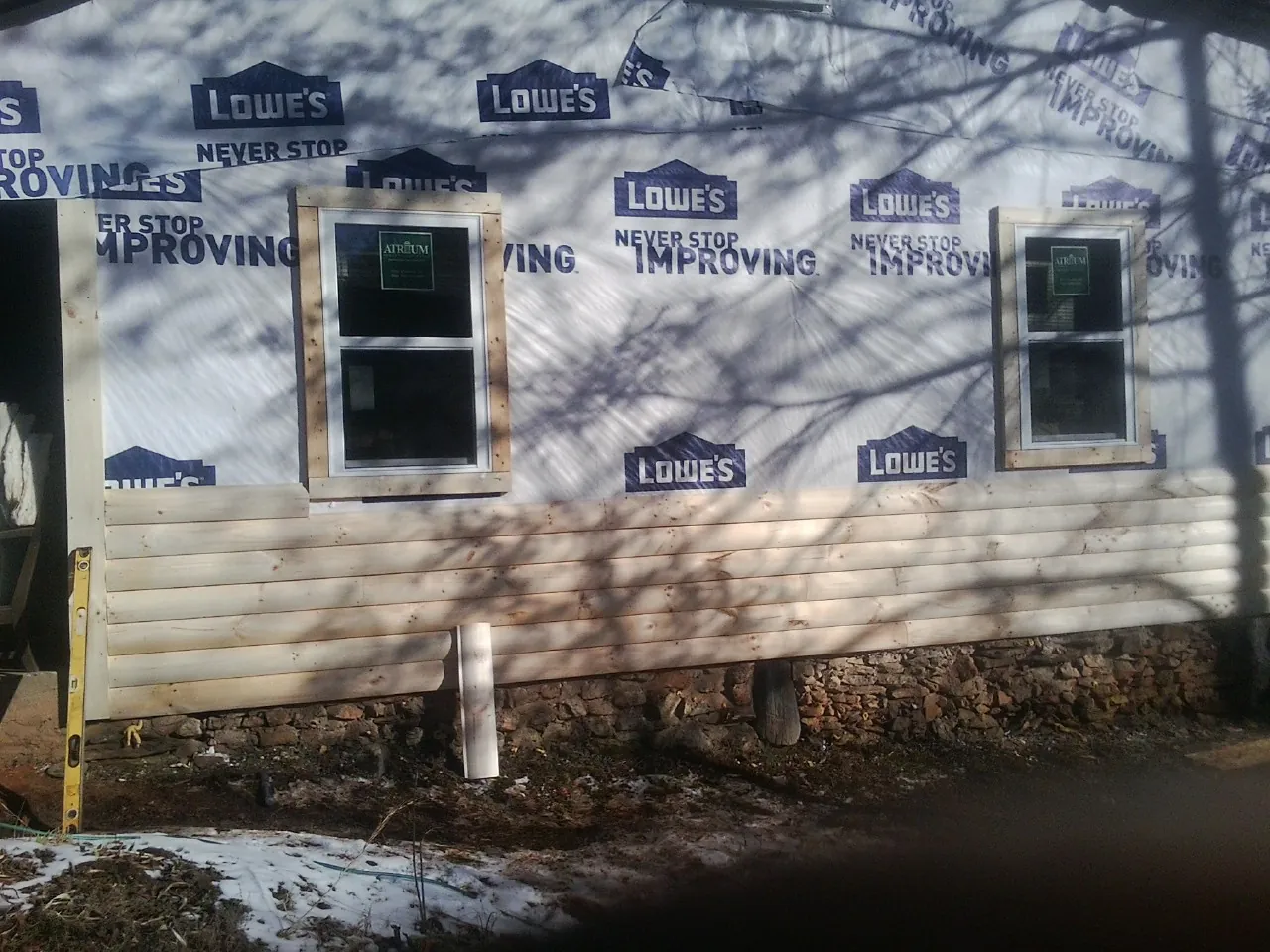 House wrap and new log siding going up on an exterior wall in Jackson Center