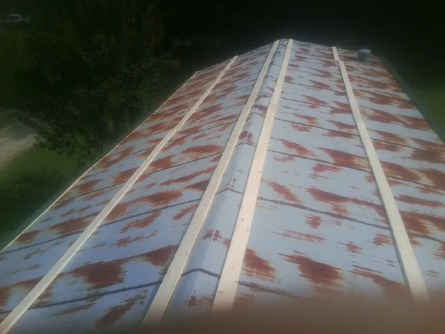 Rusted metal roof panels with new wood purlins before replacement — Storm Damage Roof Repair in Jackson Center by Roofing Brothers