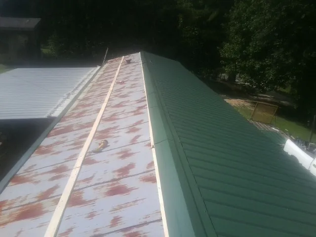 Old rusted panels beside newly installed green metal roofing — Wind Damage Roof Repair by Roofing Brothers in Jackson Center