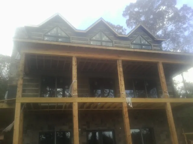 Dormers and porch framing on a large log home under construction — Roof Coating work by our crew in Jackson Center