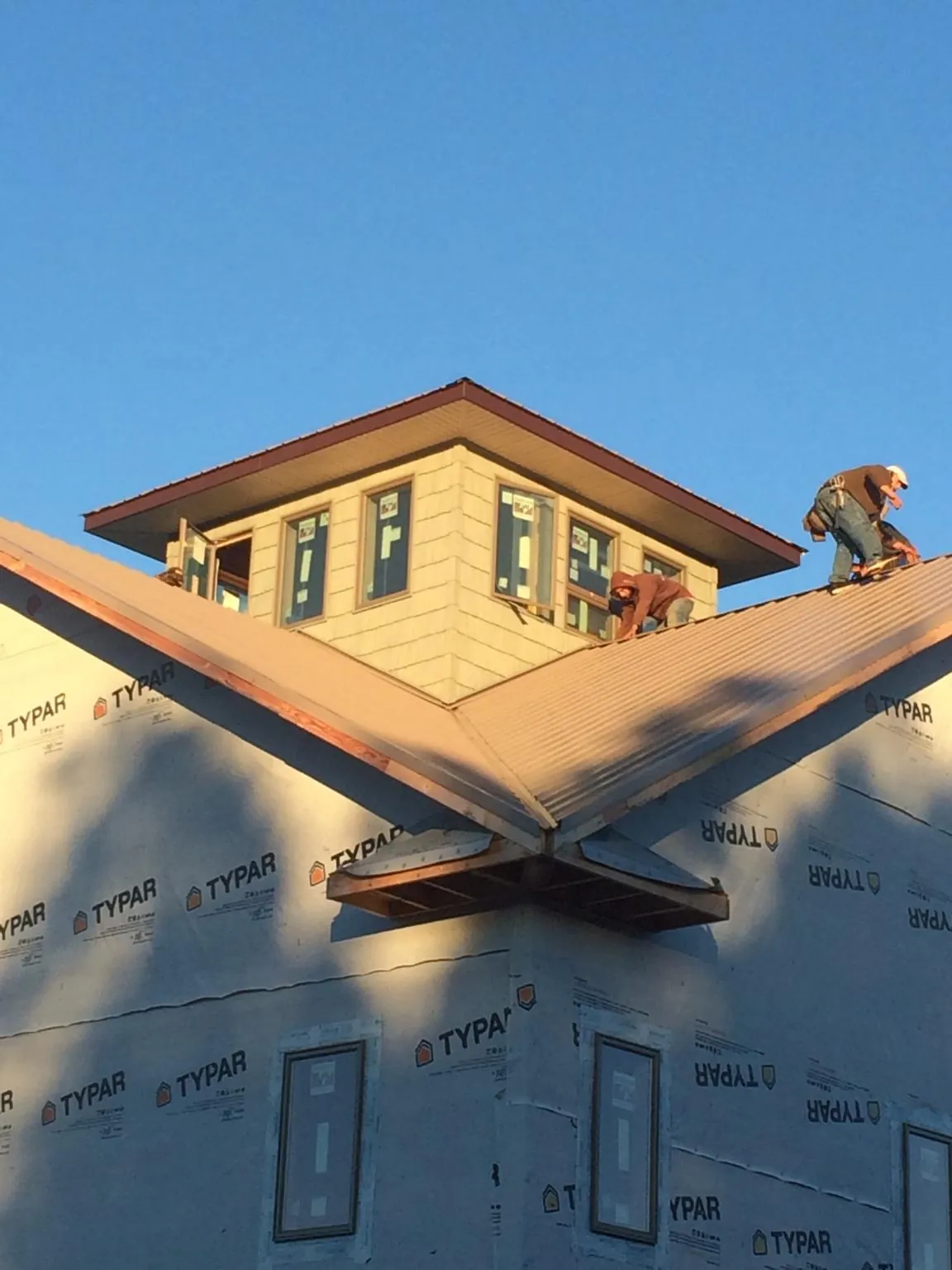 Roofers working around a rooftop cupola on a new metal roof at sunset — Roof Waterproofing in Jackson Center by Roofing Brothers